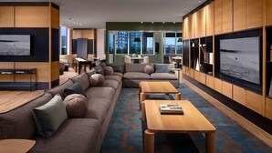 A modern living room with a sectional sofa, wooden coffee tables, and large wall-mounted TVs.