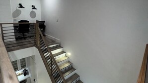 A modern staircase with wooden steps and metal railings, leading to a second-floor area with a desk and chair. - Modern Luxury Townhouse –  3-Suite Retreat (Mesa)