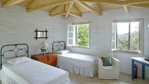 Ein Schlafzimmer mit zwei Einzelbetten, einer Holzbalkendecke, einem Fenster und einem kleinen Tisch.