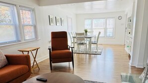 Amplia sala de estar con una mesa de centro redonda, un sofá y un comedor al fondo.