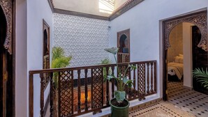 A courtyard with a wooden railing, a potted plant, and a patterned wall. - Elegant Riad Musée: Authentic Marrakech Charm in the Medina (marrakech)