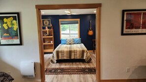 Un dormitorio con cama, ventana, una guitarra y aire acondicionado de pared.
