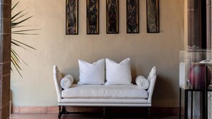 Un sofá blanco con un cojín, una lámpara de pared y cuatro cuadros enmarcados.