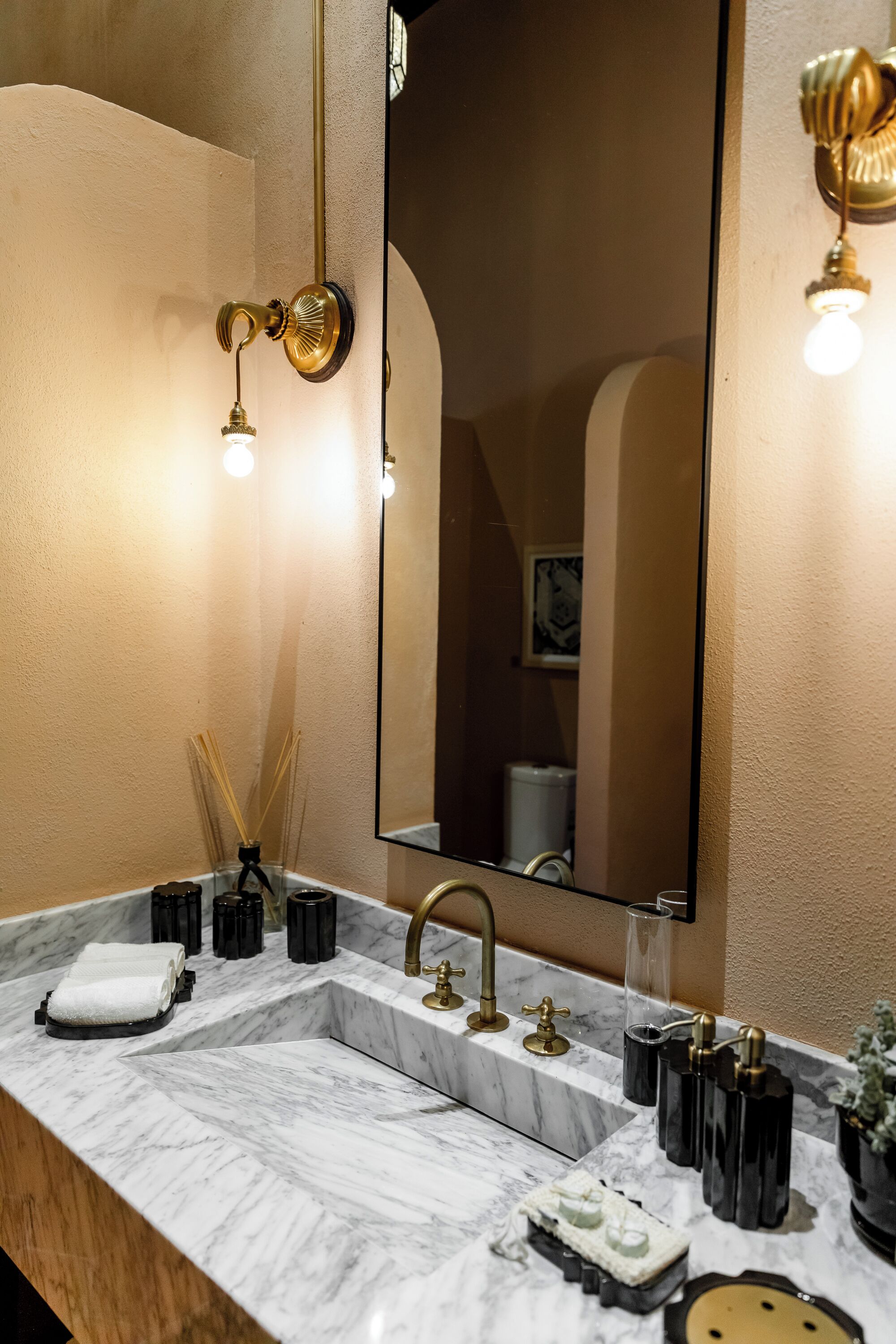A bathroom with a marble sink, gold fixtures, and a large mirror.