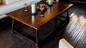 Una habitación con una mesa de centro de madera, sofá blanco y cuadros en la pared.