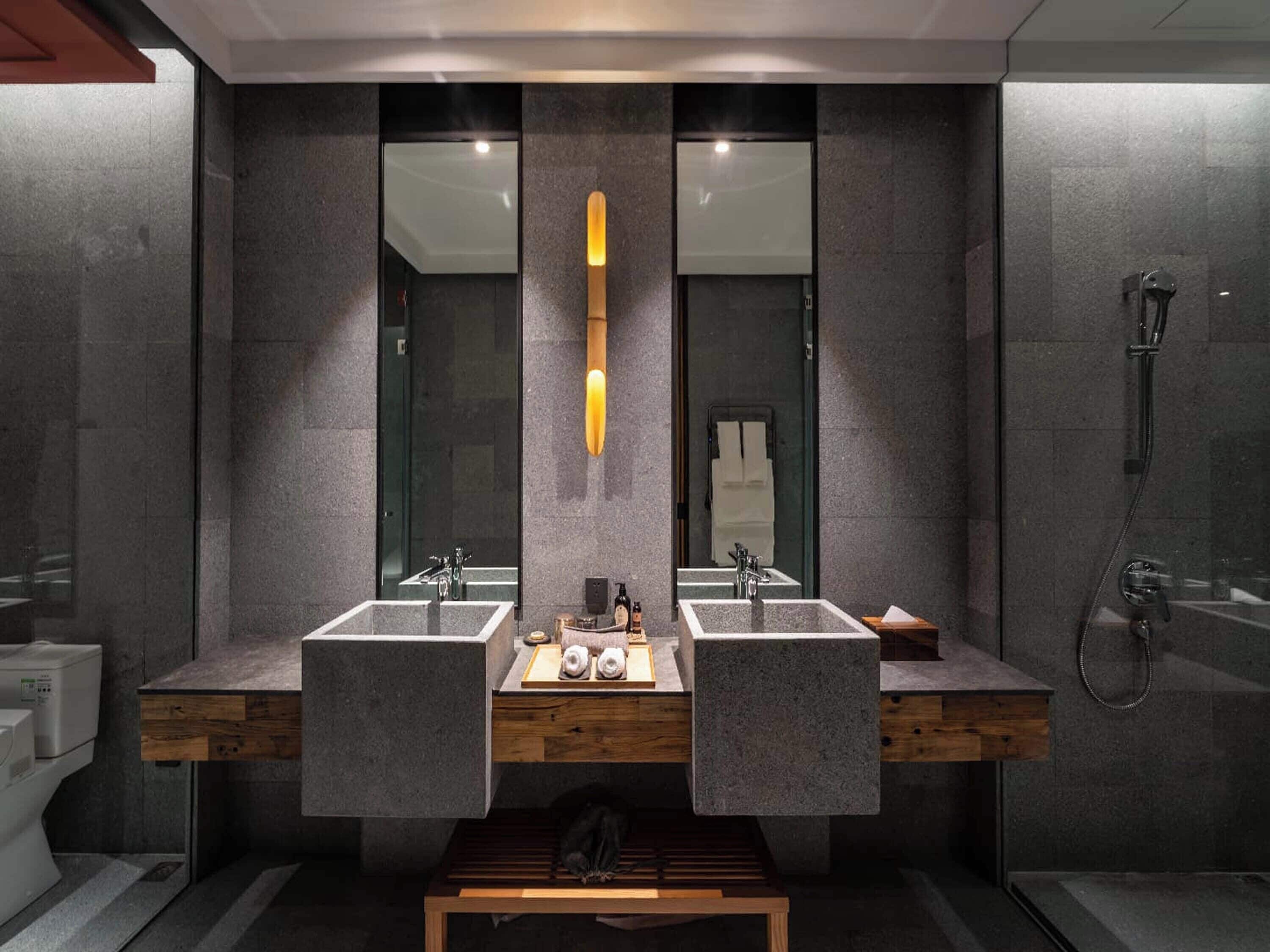 Un baño moderno con dos lavamanos, un tocador de madera y cabina de ducha de vidrio.
