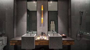 Un baño moderno con dos lavamanos, un tocador de madera y cabina de ducha de vidrio.