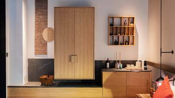 A modern bedroom with a wooden wardrobe, a bedside table with a lamp, and a small shelf with decorative items.