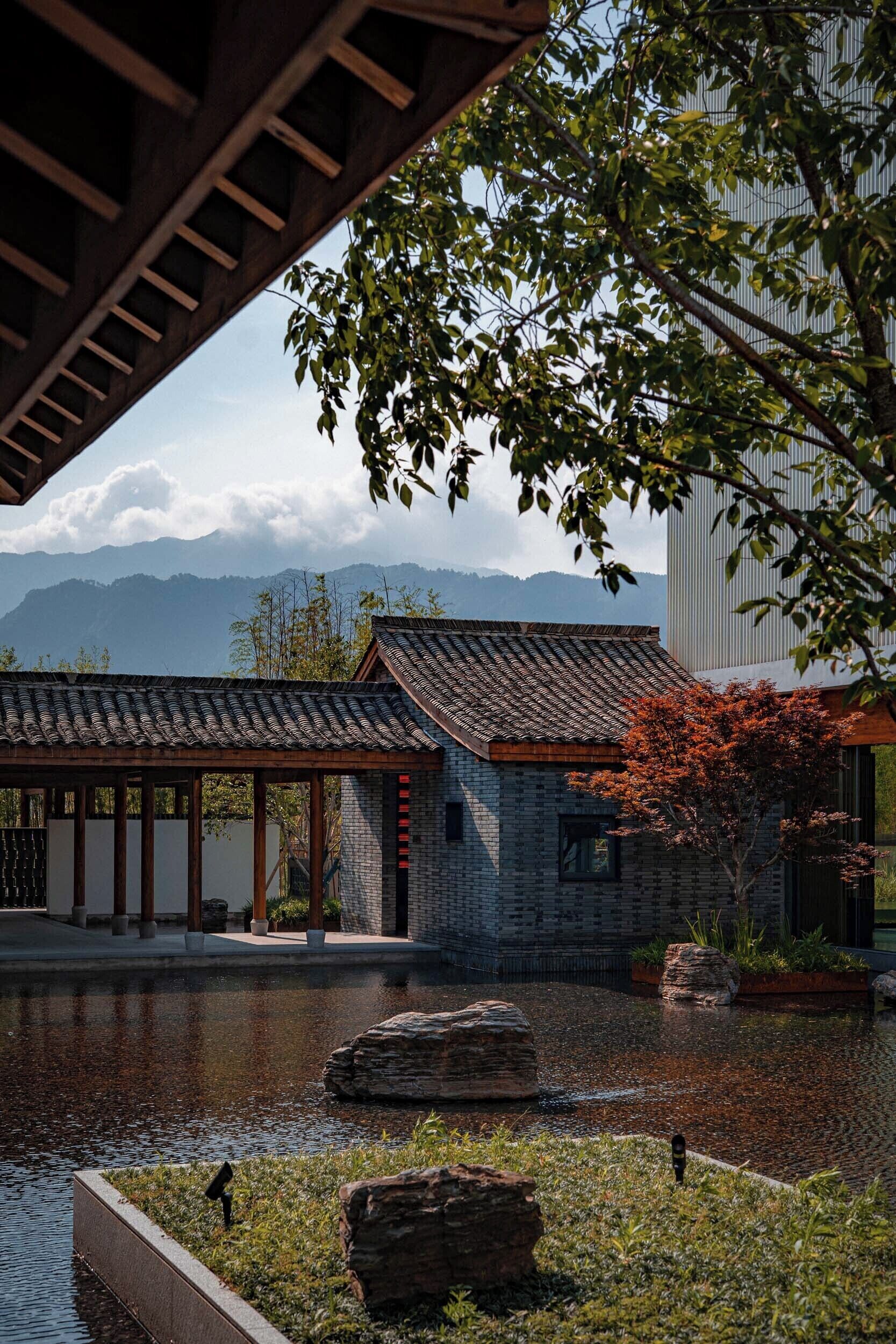 A traditional building with a tiled roof, a stone wall, and a wooden structure with a slanted roof.
