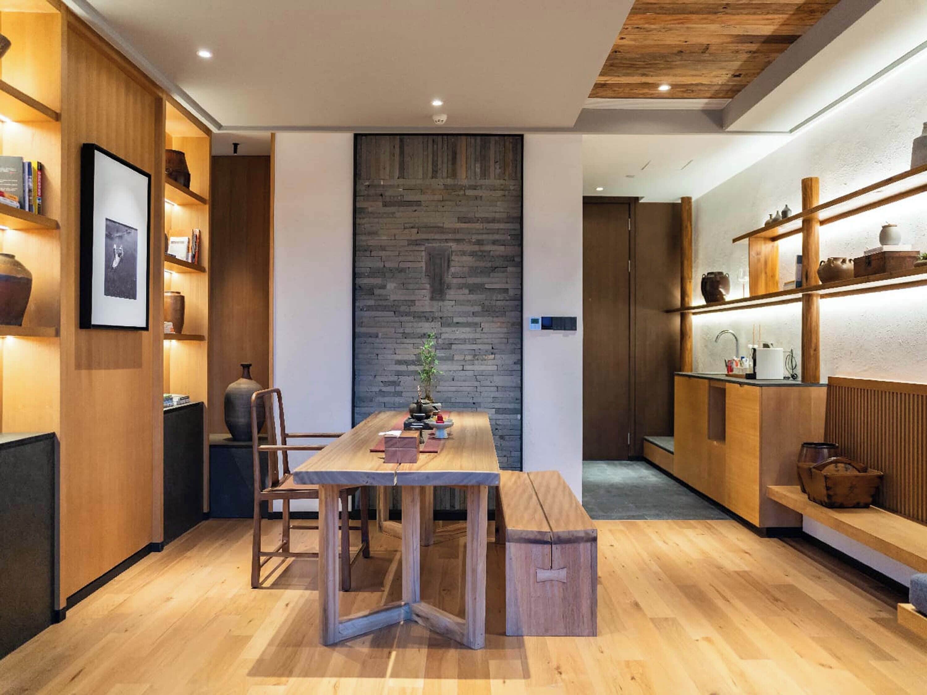 A modern kitchen with wooden cabinetry, a central island, and a stone accent wall.