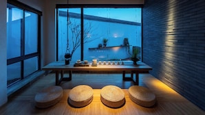 A modern interior with a wooden table, four woven stools, and a view of the sky through large windows. - Tan She Tang Quan Resort Hotel-Huangshan (Huangshan)