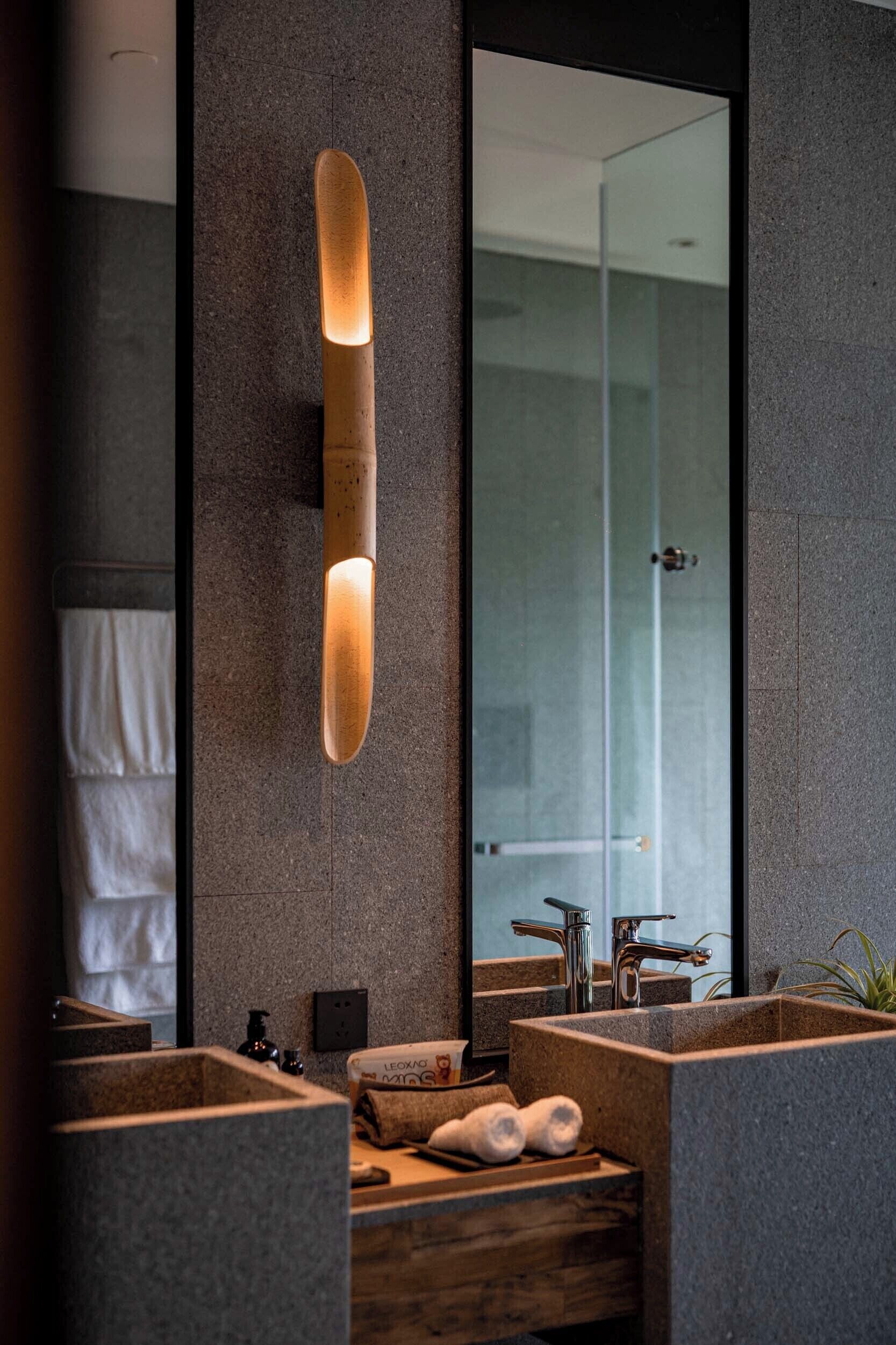 Un baño moderno con un espejo grande, dos lavamanos y un banco de madera.