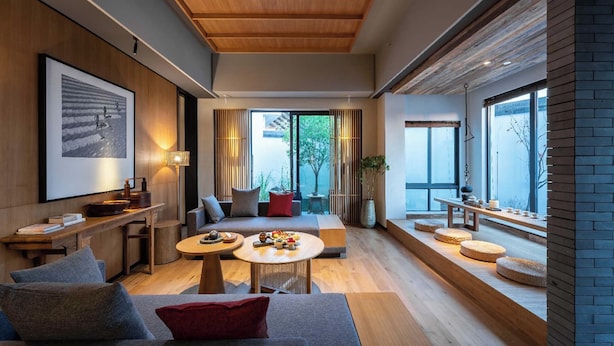 A modern living room with a wooden ceiling, a large window, and a cozy seating area. - Tan She Tang Quan Resort Hotel-Huangshan (Huangshan)