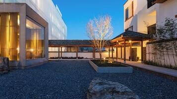 Un edificio moderno con patio, ventanas grandes y un árbol.
