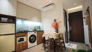 A compact kitchen with a washing machine, microwave, and a dining area with a table set for two.