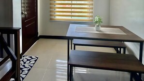 A room with a wooden door, a window with blinds, a small table with a plant, and a tiled floor. - Spacious family-friendly apartment with Balcony! (Muntinlupa)