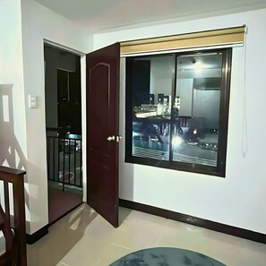 Ein Zimmer mit einer Schiebetür, die auf einen Balkon führt, einem großen Fenster mit Aussicht und einem kleinen runden Tisch.