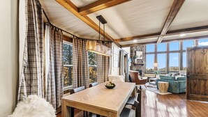 Un coin repas avec une table et des chaises en bois, des rideaux à carreaux et un luminaire suspendu.