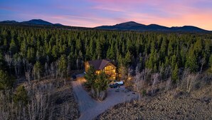 Un chalet entouré d’une forêt dense, avec un sentier bien tracé menant à l’entrée.