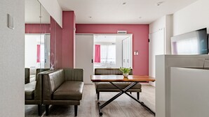 Una sala moderna con un sofá, una mesa de comedor con una planta y un televisor.