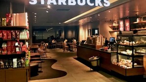 Una tienda Starbucks con zonas de estar y una exhibición de pasteles.