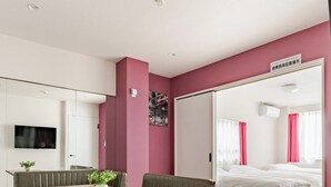 Una habitación de hotel moderna con zona de comedor, cama y televisor.