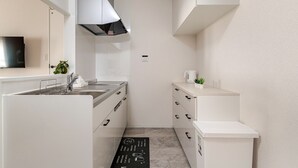 Una cocina moderna con armarios blancos, una campana extractora de acero inoxidable, un fregadero y una encimera con una pequeña planta.