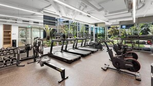 Une salle de sport équipée de tapis de course, de vélos elliptiques et de poids libres.