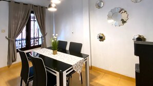 A dining area with a table, chairs, and a hanging light fixture. - Homestay Syariah Merapi View Simply Homy (Ngaglik)