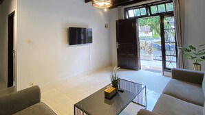 A modern living room with a sofa set, a coffee table, and a TV mounted on the wall. - Homestay Syariah Merapi View Simply Homy (Ngaglik)
