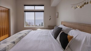 Une chambre avec un grand lit, une armoire en bois, une fenêtre donnant sur un beau paysage et un élément décoratif fixé au mur.