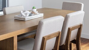 Un coin repas avec une table en bois, quatre chaises, un luminaire suspendu et un tableau au mur.