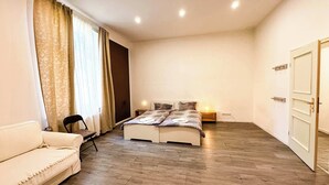 A bedroom with a bed, a white sofa, a chair, and a door.