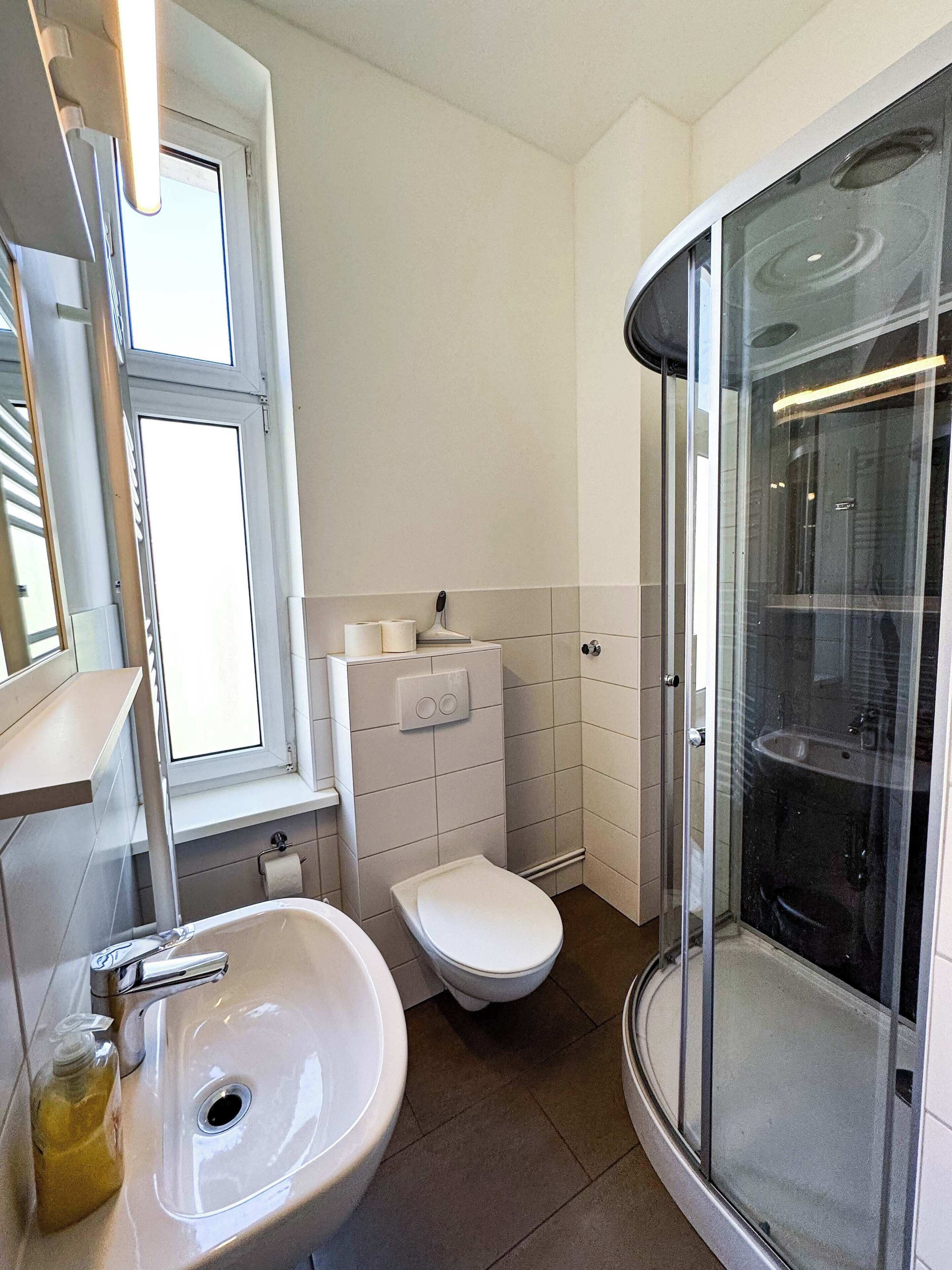 Ein modernes Badezimmer mit Waschbecken, Toilette und Duschkabine aus Glas.
