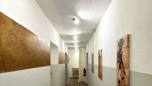 Un pasillo con piso de madera, paredes blancas y obras de arte en las paredes.