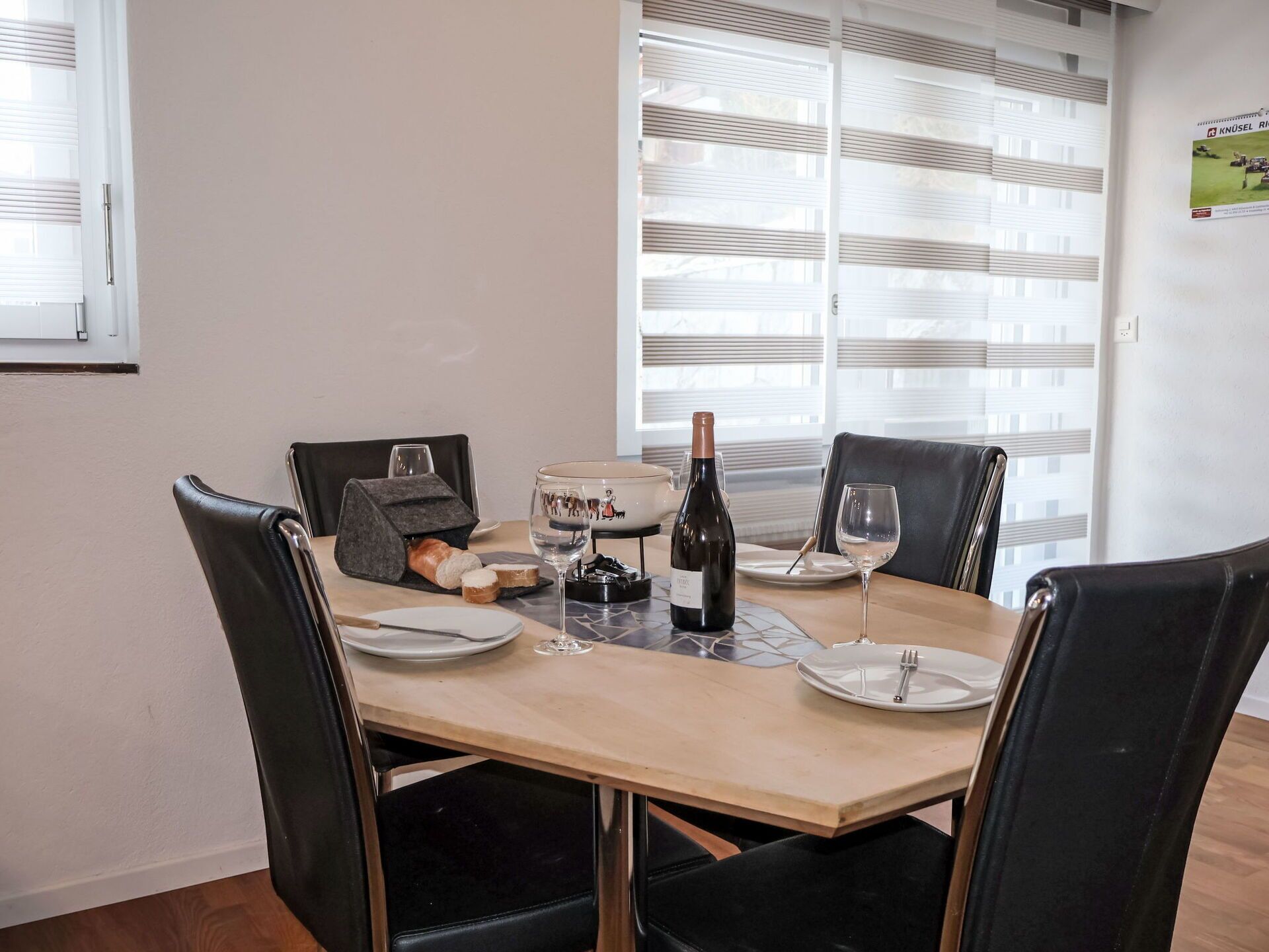 Et spisebord dækket med tallerkener, glas, en vinflaske og en brødløber.