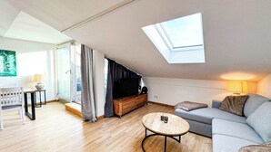Una sala de estar moderna con tragaluz, un sofá, una mesa de centro y un mueble para televisión.