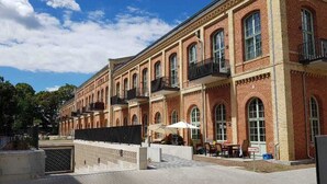 Un gran edificio de ladrillo con varios balcones y un patio con mesas al aire libre.