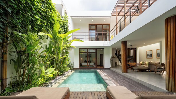Ein modernes Haus mit einem zentral gelegenen Schwimmbad, einer Holzterrasse und einem Balkon mit Blick auf das Schwimmbad.