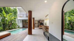 Ein modernes Interieur mit Pool, Holzboden und Essbereich mit Blick auf den Pool.