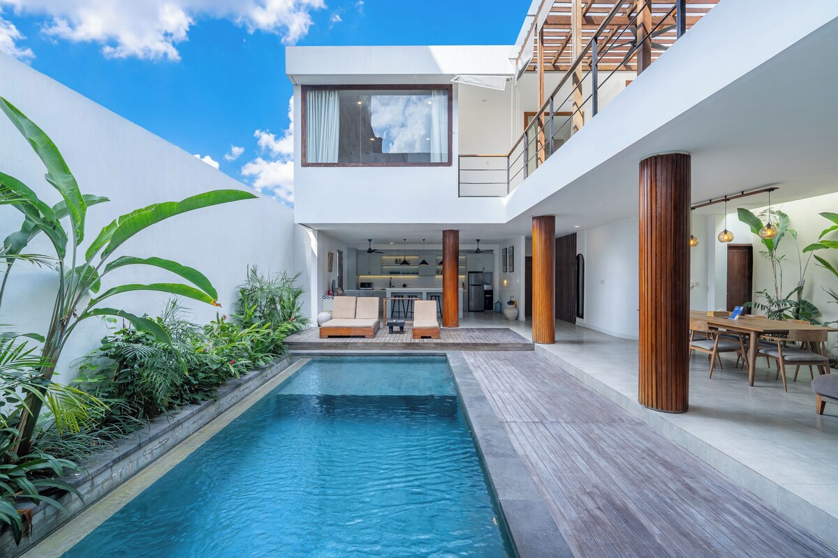 Une maison moderne dotée d’une piscine, d’une terrasse en bois et d’un espace repas.