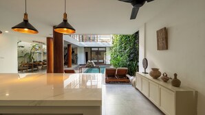 Ein großzügiger Wohnbereich mit Pool, Holzmöbeln und Deckenventilator.