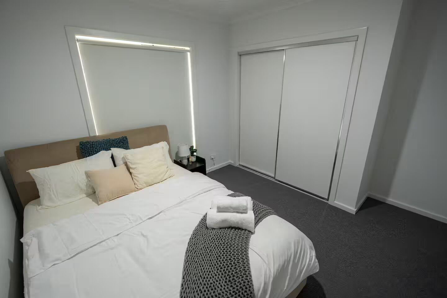 Ein Hotelzimmer mit Bett, Nachttisch, Kleiderschrank und Wandleuchte.