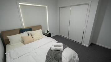 Ein Hotelzimmer mit Bett, Nachttisch, Kleiderschrank und Wandleuchte.
