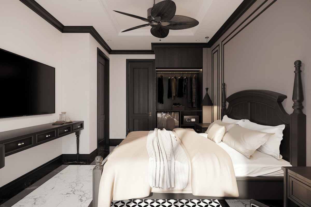 Une chambre à coucher avec un grand lit, une télévision, une armoire et un ventilateur de plafond.