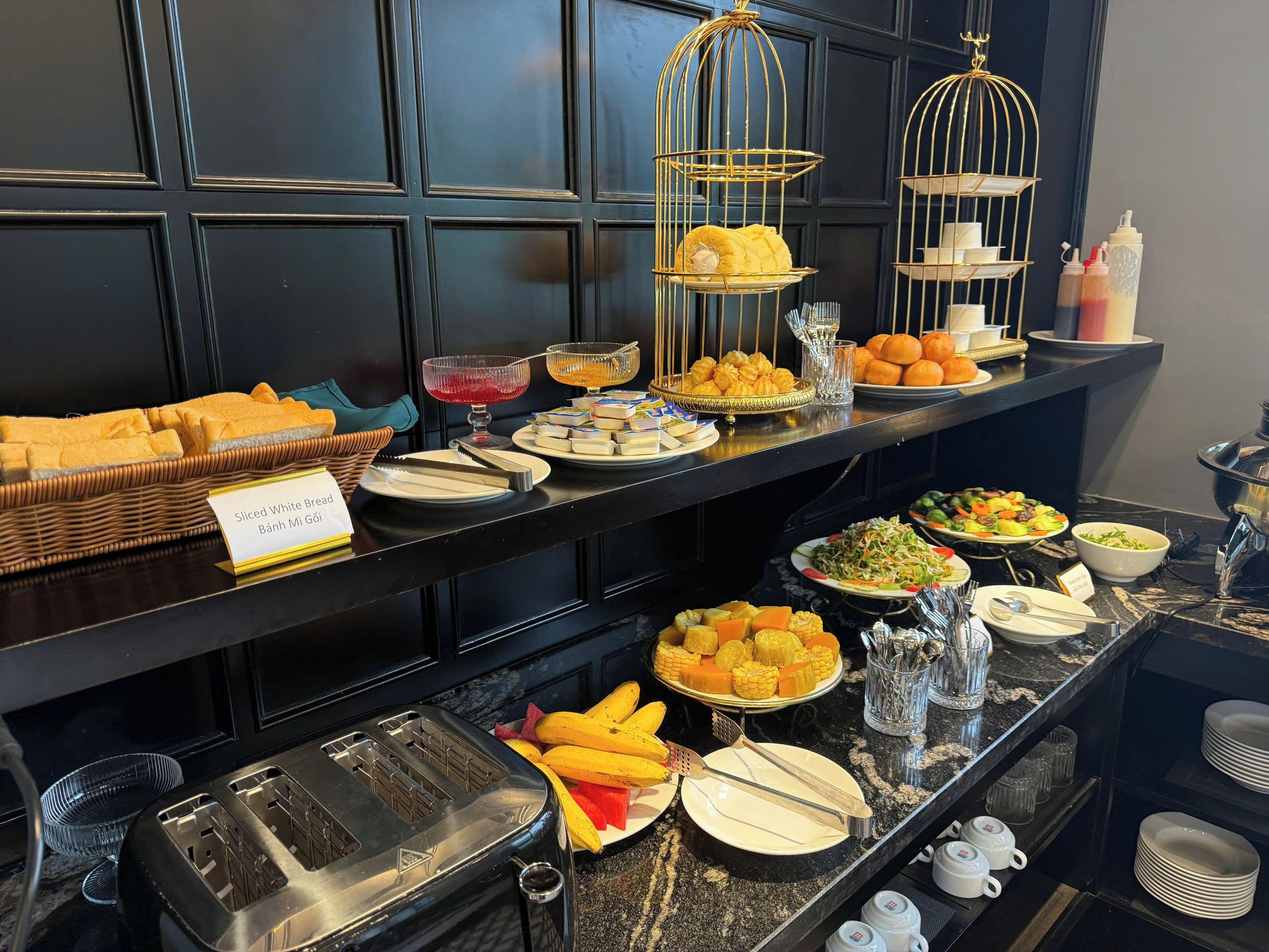 Un buffet proposant une variété d’aliments, notamment des tranches de pain blanc, des fruits et une salade.