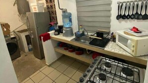 Eine kleine Küche mit Gasherd, Mikrowelle und Wasserspender.