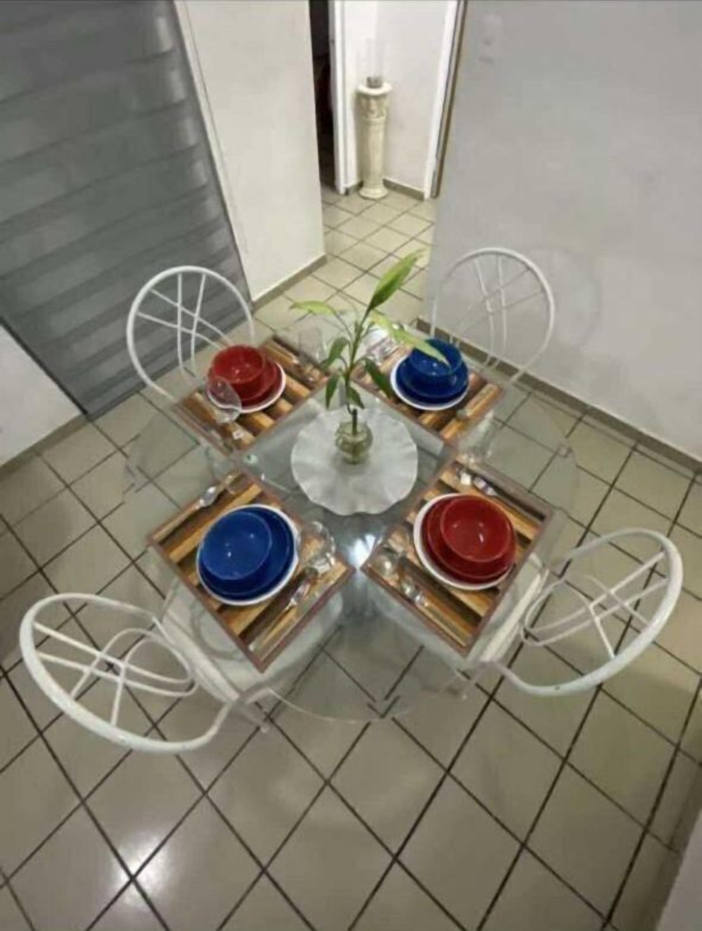 A small, square dining table with four chairs, a potted plant, and a vase.