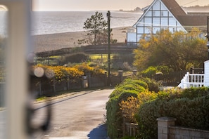 A coastal road with a white house, a wooden fence, and a beach in the background. - 2 Truman Lodge, Thorpeness (Thorpeness)