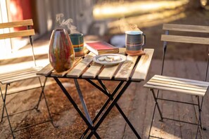 Une table en bois avec un cadre en métal, un vase, une tasse, une assiette avec des biscuits et un livre.